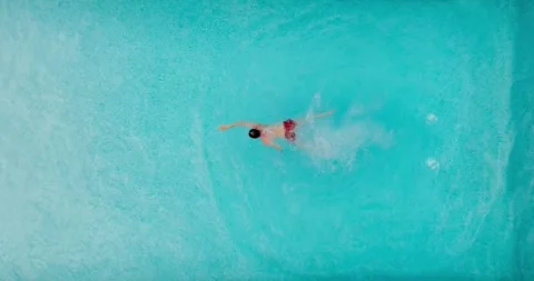 Aerial view as a man dives into the pool and swims, slow motion Stock Footage 242534268