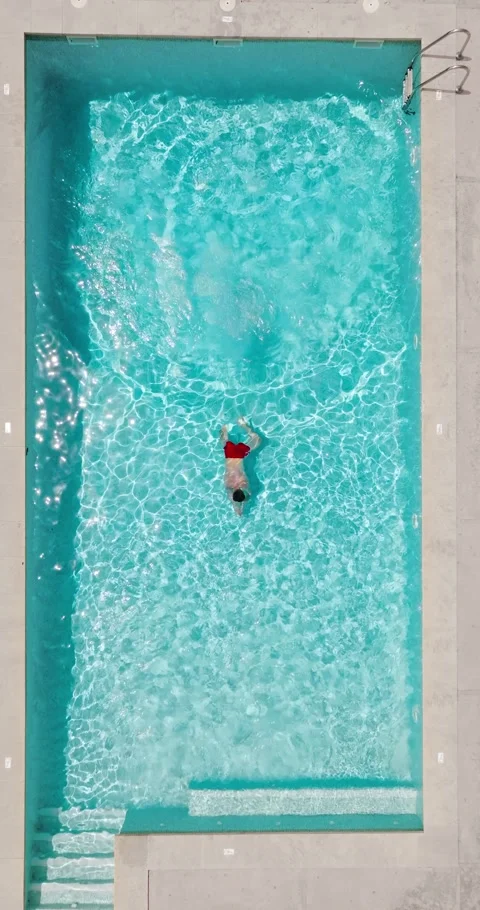 Aerial view as a man dives into the pool and swims. Slow motion Stock Footage 340408018