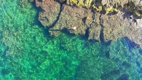 Aerial view of a man diving into the crystal-clear turquoise waters of the Stock Footage 344322528