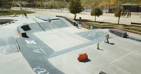 AERIAL VIEW OF MAN DOING TRICKS WITH A SCOOTER IN A SKATE PARK 4K Stock Footage 102379202