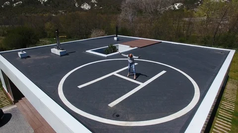 Aerial view. Man doing workout on helipad on roof of house. Open air stretch Stock Footage 129961567