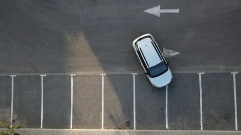 Aerial view of a man forward parking a car, getting out of it and walking away Stock Footage