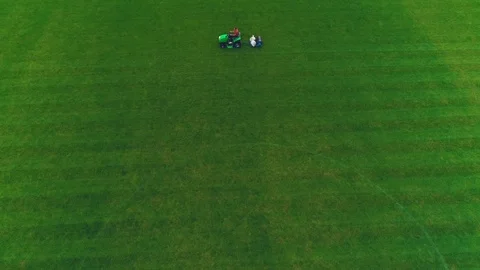 Aerial view of man at his work cutting the football lawn. 4K. Stock Footage 110837149