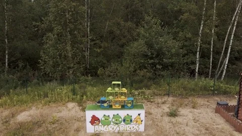 Aerial view man knocking down plushies with giant slingshot on edge of forest Stock Footage 72287638