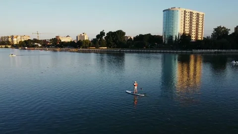 Aerial view of a man on the lake, study floating on a surfboard in a life jacket Stock Footage 140986732