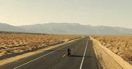 Aerial View Of Man Riding Motorcycle Down Desert Road At Sunset Stock Footage
