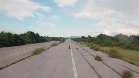 Aerial view of man riding a powerful motorcycle at abandoned airfield. Stock Footage 149003283