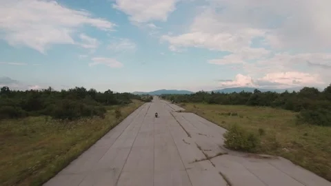 Aerial view of man riding a powerful motorcycle at abandoned airfield. Stock Footage 149003309