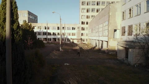Aerial view of a man running between the buildings of an old abandoned factory Stock Footage 219407811