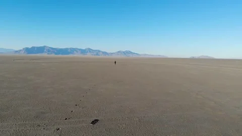 Aerial View of Man Running on Desert Salt Flats With Mountains in the Horizon Stock Footage 142306876