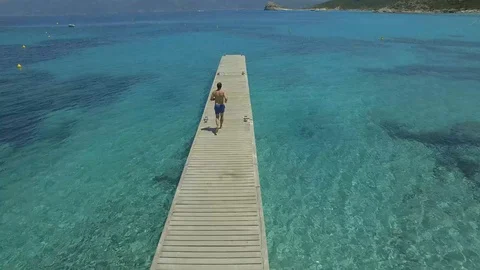 Aerial view of man running down pier towards open ocean, Corsica Stock Footage 85471115