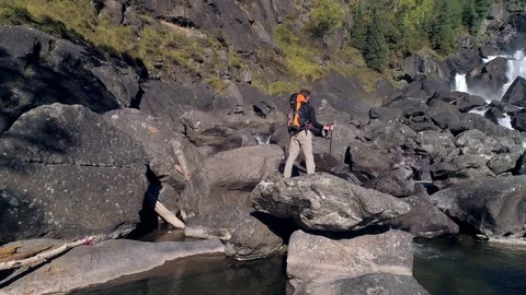 Aerial view of man standing in front of a waterfall river with rocks, autumn Video stock 81646046