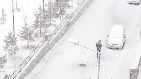 Aerial view of a man trekking through heavy snow, leaving a trail of footprints Stock Footage 236947307