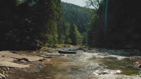 Aerial view of a man walking along a river in a mountain canyon. Stock Footage 265559532