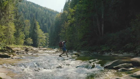 Aerial view of a man walking along a river in a mountain canyon. Stock Footage 265560021