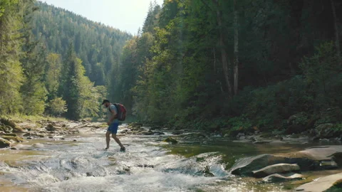 Aerial view of a man walking along a river in a mountain canyon. Stock Footage 265560265
