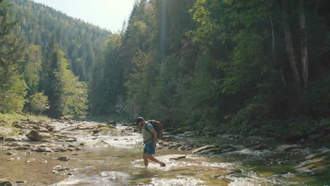 Aerial view of a man walking along a river in a mountain canyon. Stock Footage 265560945