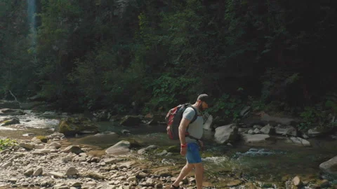 Aerial view of a man walking along a river in a mountain canyon. Stock Footage 265561595