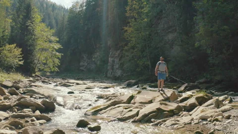 Aerial view of a man walking along a river in a mountain canyon. Stock Footage 265561688