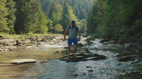 Aerial view of a man walking along a river in a mountain canyon. Stock Footage 265561915