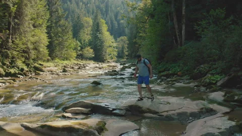 Aerial view of a man walking along a river in a mountain canyon. Stock Footage 265562241
