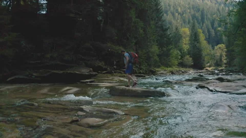 Aerial view of a man walking along a river in a mountain canyon. Stock Footage 265562528