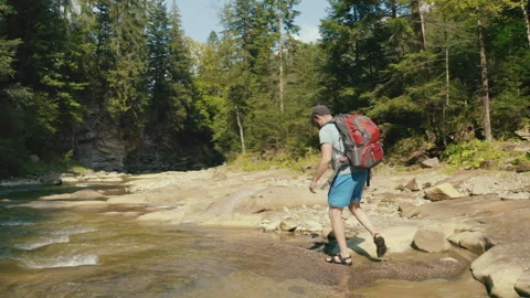 Aerial view of a man walking along a river in a mountain canyon. Stock Footage 265562652