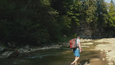 Aerial view of a man walking along a river in a mountain canyon. Stock Footage 265562871