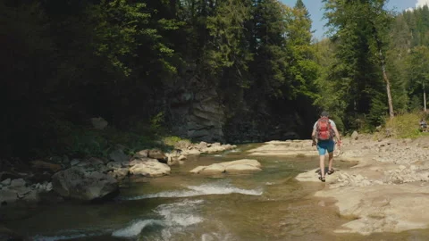 Aerial view of a man walking along a river in a mountain canyon. Stock Footage 265563027