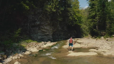 Aerial view of a man walking along a river in a mountain canyon. Stock Footage 265563259