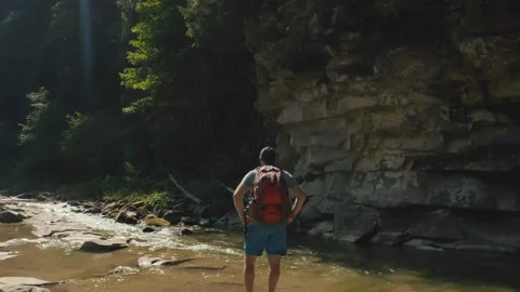 Aerial view of a man walking along a river in a mountain canyon. Stock Footage 265564193