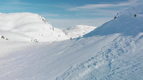 Aerial view of man walking through snow valley in mountain landscape Stock Footage 145890699