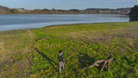Aerial View Of A Man Walking Through The Meadows By The Lakeshore. Stock Footage 264637687