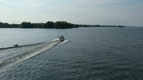Aerial view of man water skiing behind a boat with a clear sky on a sunny Stock Footage 202010429