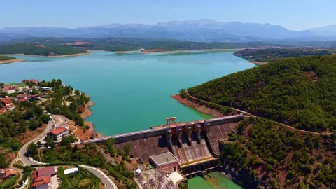Aerial View of a Massive Dam and Stunning Emerald Reservoir Nestled in Mountains Stock Footage 341394371