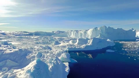 Aerial view of massive icebergs floating in arctic ocean water under bright blue Stock Footage 343696014