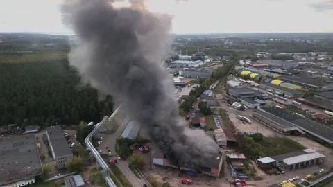 Aerial view of massive industrial fire with thick black smoke and fire trucks Stock Footage 321362038