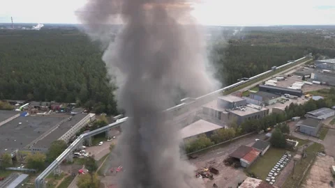Aerial view of massive industrial fire with thick black smoke and fire trucks Stock Footage 321362618