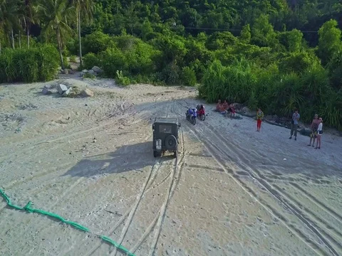 Aerial View Military Jeep Drives on Beach to Tropical Woods Stock Footage