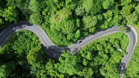 Aerial view of a minivan driving along a winding mountain road. Stockbeeldmateriaal 342343435