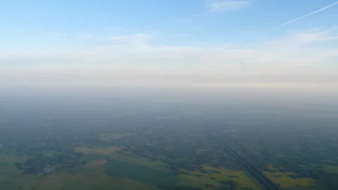 Aerial view of misty green fields and forest under blue sky Video stock 338354487