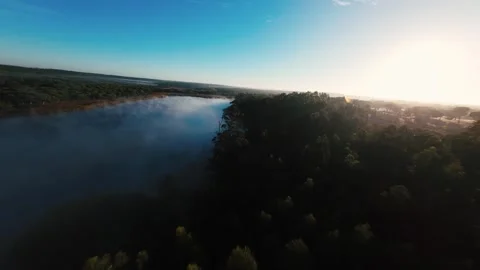 Aerial view of misty river, glowing sunrise, and forested land Stock Footage 340904048