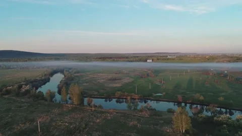 Aerial view of a misty river surrounded with green trees at foggy sunrise. Calm Video stock 196230608