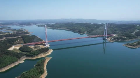 Aerial view of a modern cable-stayed bridge spanning a calm river valley Stock Footage 347037774