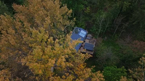 Aerial view of modern forest cabin roof, deck, and autumn trees Stock Footage 324796042