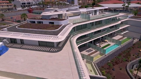 Aerial View of Modern Multi-Level Building with Rooftop Terraces and Pools in Stock Footage 344250717