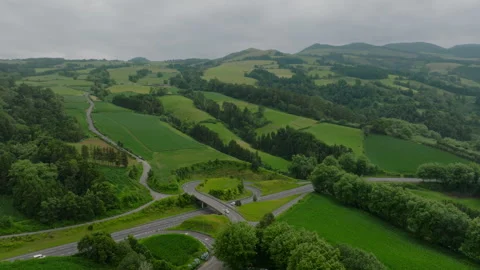 Aerial view of a modern road interchange nestled within the lush, rolling green Vidéo 335720997