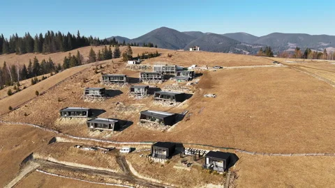 Aerial view of modular cabins under construction on dry mountain slope in Stock Footage 306702978