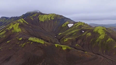 Aerial view of moss-covered volcanic mountain with summit crater and snowfields, Stock Footage 341606379