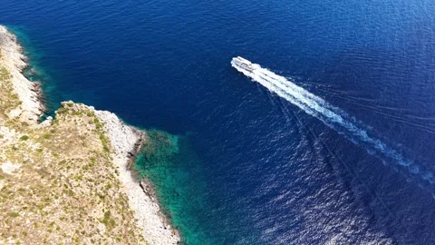 Aerial view of a motorboat navigating through deep blue waters near rock Vidéo 344568995
